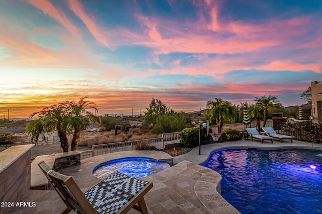 pool at dusk featuring a patio and a hot tub