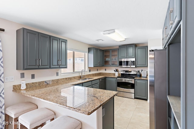 kitchen with stainless steel appliances, sink, gray cabinetry, and kitchen peninsula