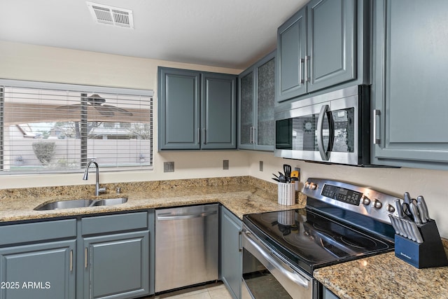 kitchen featuring sink, light tile patterned floors, stainless steel appliances, and light stone countertops