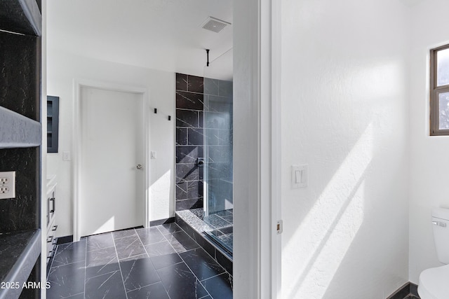 bathroom with toilet and a tile shower