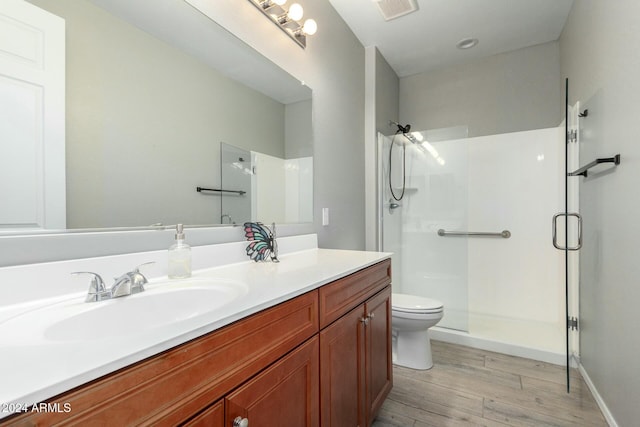 bathroom with wood-type flooring, vanity, toilet, and walk in shower