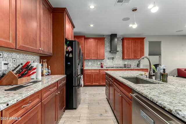 kitchen with sink, light hardwood / wood-style flooring, wall chimney exhaust hood, light stone countertops, and appliances with stainless steel finishes