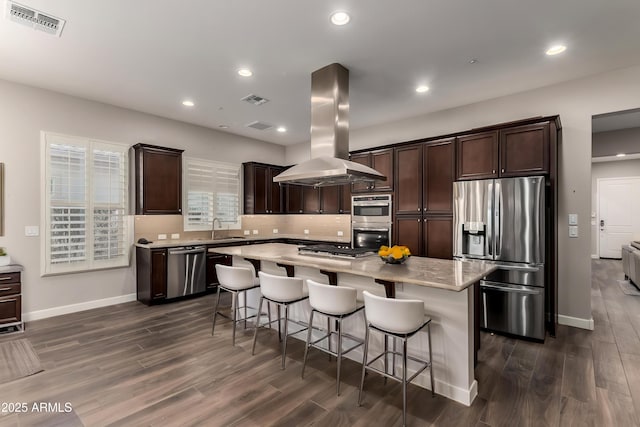 13448 W Miner Trl, Peoria, AZ 85383 - kitchen with appliances with stainless steel finishes, island exhaust hood, dark wood finished floors, dark brown cabinets, and recessed lighting