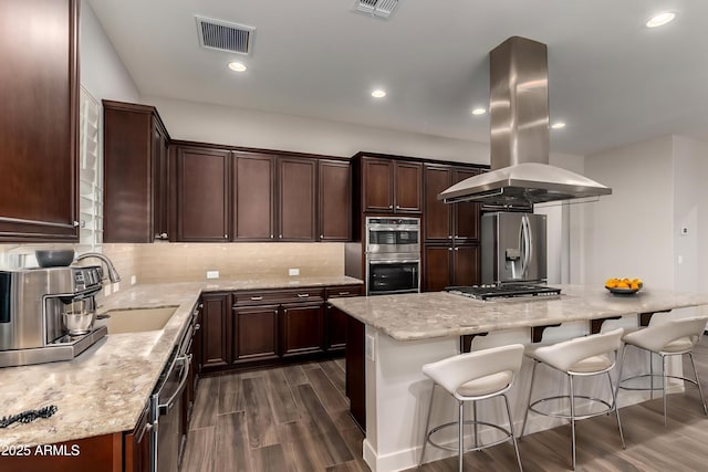 13448 W Miner Trl, Peoria, AZ 85383 - kitchen with stainless steel appliances, island range hood, dark wood-style floors, a kitchen bar, and tasteful backsplash