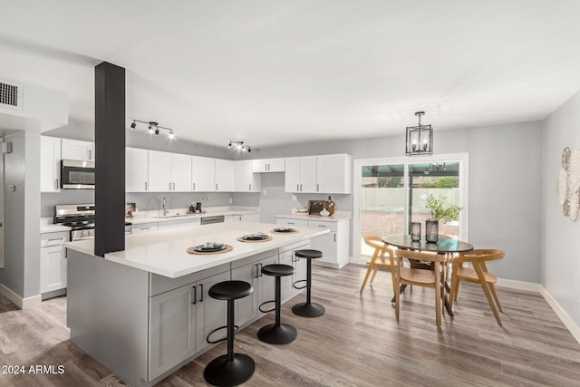 kitchen with white cabinets, a kitchen island, light wood-type flooring, and appliances with stainless steel finishes