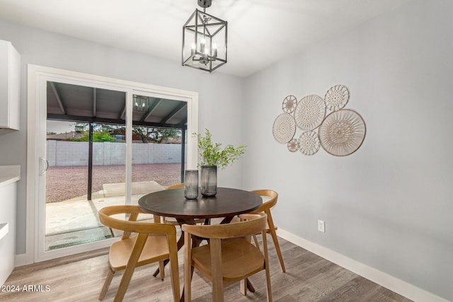 dining area with light hardwood / wood-style floors and an inviting chandelier