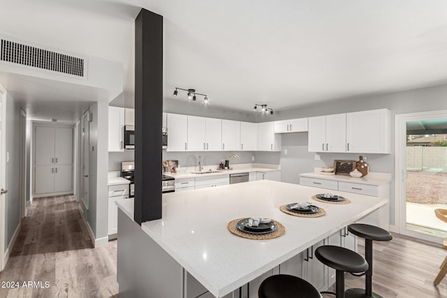 kitchen with white cabinetry, a center island, light wood-type flooring, and appliances with stainless steel finishes