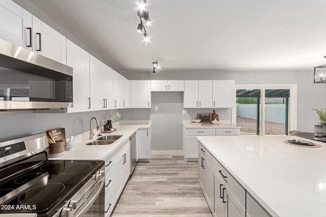 kitchen with light hardwood / wood-style floors, white cabinetry, sink, and appliances with stainless steel finishes