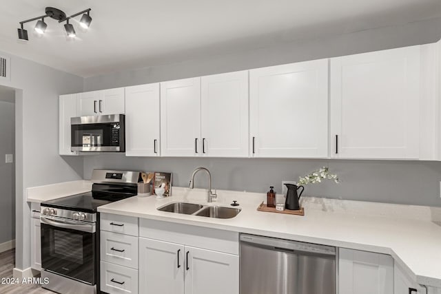 kitchen with sink, white cabinets, stainless steel appliances, and wood-type flooring