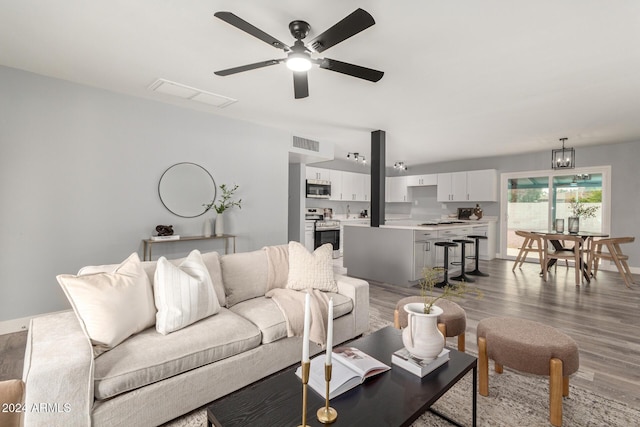 living room featuring ceiling fan with notable chandelier and wood-type flooring