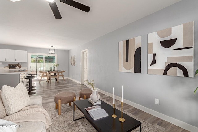 living room featuring ceiling fan with notable chandelier and light wood-type flooring