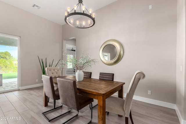 dining room with a healthy amount of sunlight, ceiling fan with notable chandelier, and light hardwood / wood-style floors