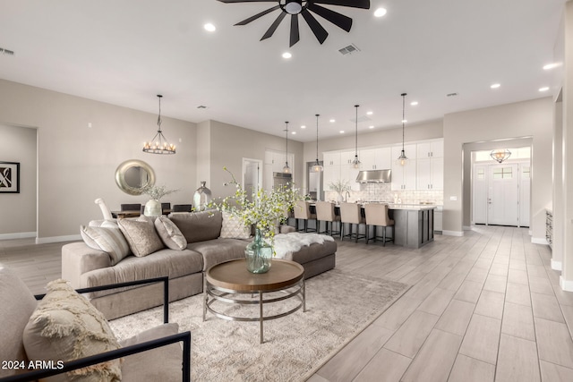 living room featuring ceiling fan with notable chandelier and light hardwood / wood-style floors