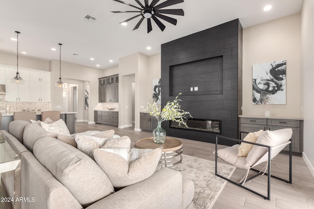 living room with ceiling fan, a fireplace, and light wood-type flooring