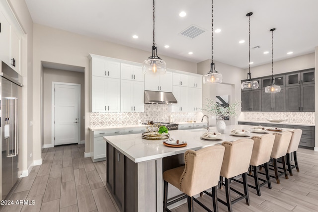 kitchen featuring a spacious island, decorative light fixtures, light hardwood / wood-style floors, white cabinetry, and stainless steel appliances