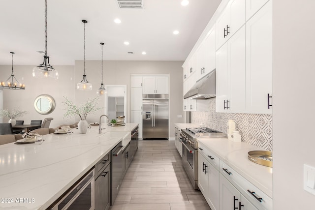 kitchen with light stone countertops, white cabinetry, hanging light fixtures, and high quality appliances