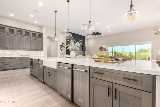 kitchen with a large island, ceiling fan, hanging light fixtures, backsplash, and appliances with stainless steel finishes