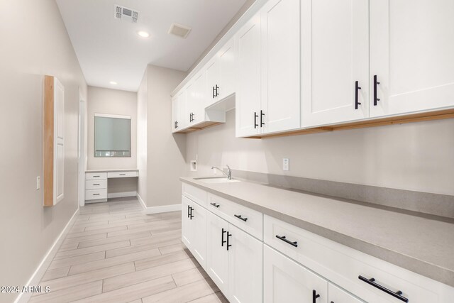 kitchen with light hardwood / wood-style flooring, white cabinets, and sink