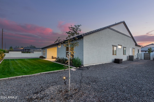 property exterior at dusk with central AC unit and a lawn