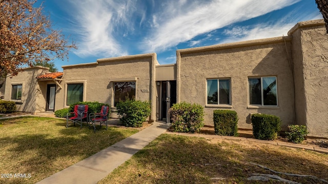 view of front of home with stucco siding and a front lawn