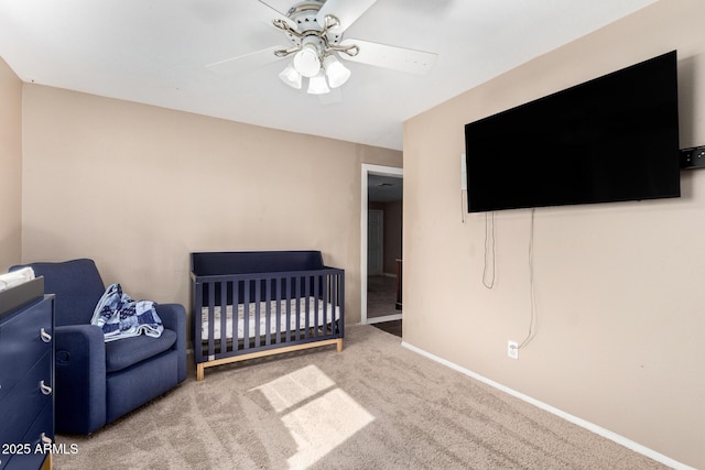 bedroom featuring a crib, ceiling fan, and carpet