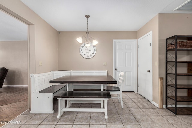 tiled dining room with a notable chandelier