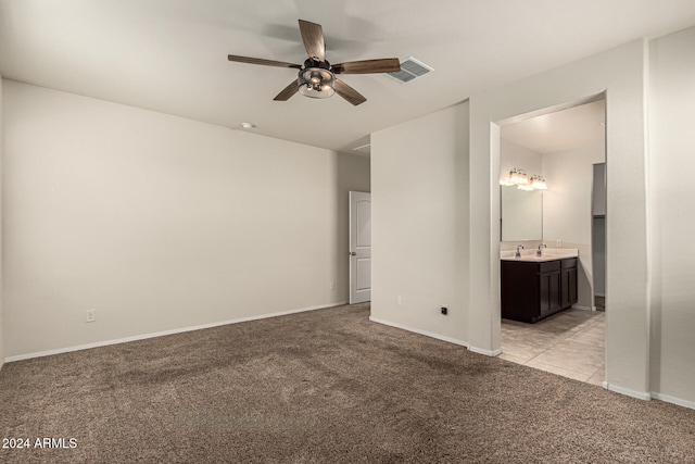 unfurnished bedroom featuring connected bathroom, ceiling fan, light carpet, and sink