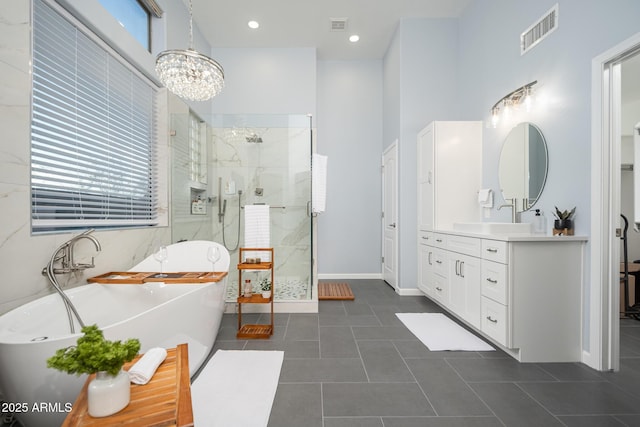 bathroom with tile patterned floors, plus walk in shower, vanity, and an inviting chandelier