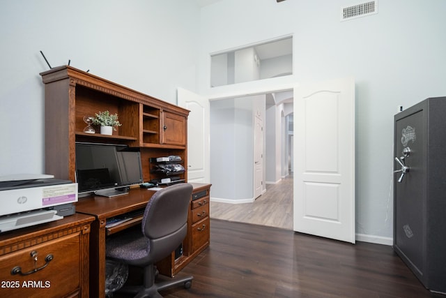 office featuring dark hardwood / wood-style floors and a towering ceiling