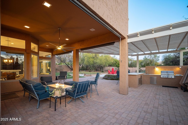 view of patio / terrace with a pergola, ceiling fan, exterior kitchen, a fire pit, and grilling area