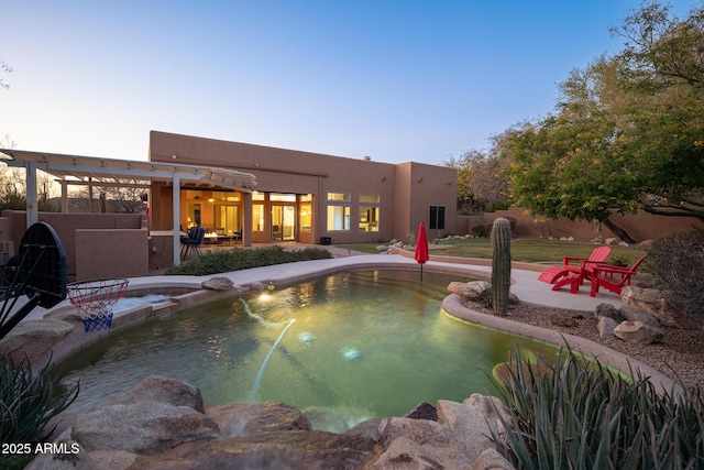 pool at dusk with a patio area and an in ground hot tub