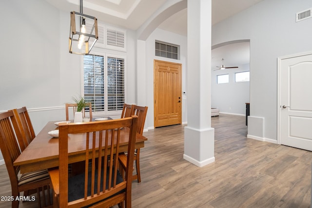 dining space featuring wood-type flooring, ceiling fan with notable chandelier, and a wealth of natural light