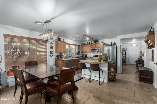 dining area with sink, a notable chandelier, a textured ceiling, and light tile patterned floors