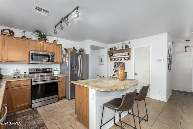 kitchen with a kitchen breakfast bar, a center island, stainless steel appliances, and light tile patterned floors