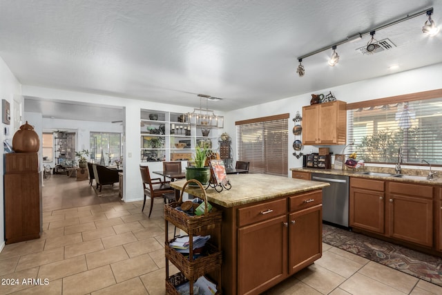 kitchen with light tile patterned floors, a kitchen island, a textured ceiling, stainless steel dishwasher, and sink