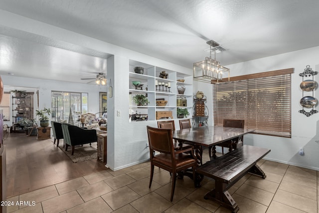 dining space with built in features, wood-type flooring, a textured ceiling, and ceiling fan with notable chandelier