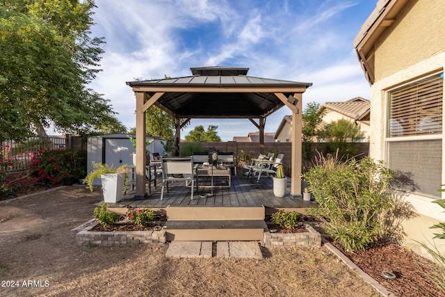 view of patio with a gazebo, a wooden deck, and a shed