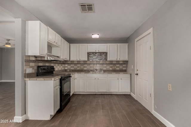 3402 W Tonto St W, Phoenix, AZ 85009 - kitchen with black range with electric cooktop, tile counters, wood tiled floors, white cabinetry, and decorative backsplash