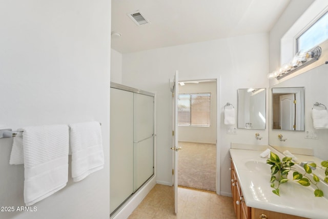 bathroom with vanity, a shower with shower door, and a wealth of natural light