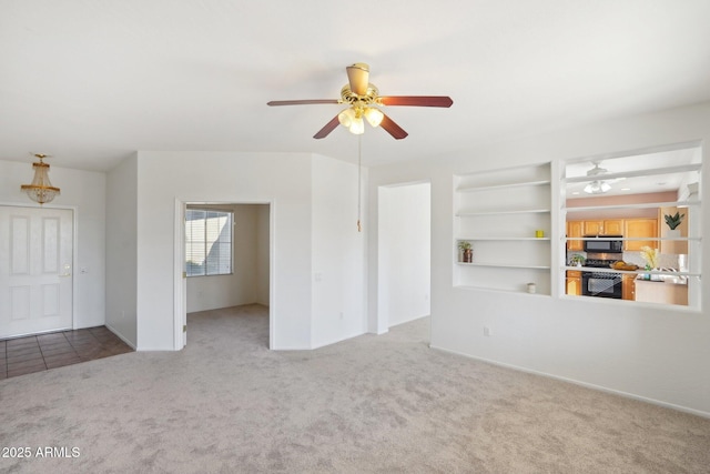 unfurnished living room featuring ceiling fan, light colored carpet, and built in features