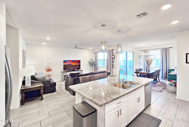 kitchen featuring white cabinetry, an island with sink, appliances with stainless steel finishes, pendant lighting, and sink