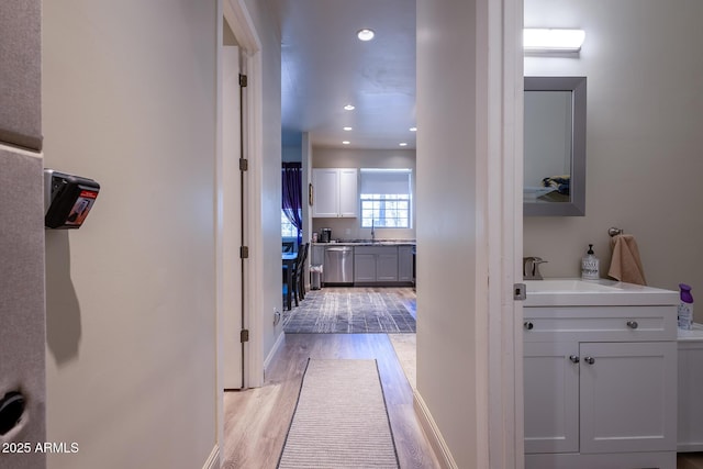 corridor with a sink, light wood-style flooring, recessed lighting, and baseboards