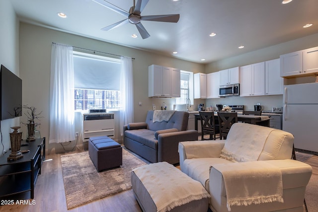 living area featuring light wood-style floors, a ceiling fan, and recessed lighting