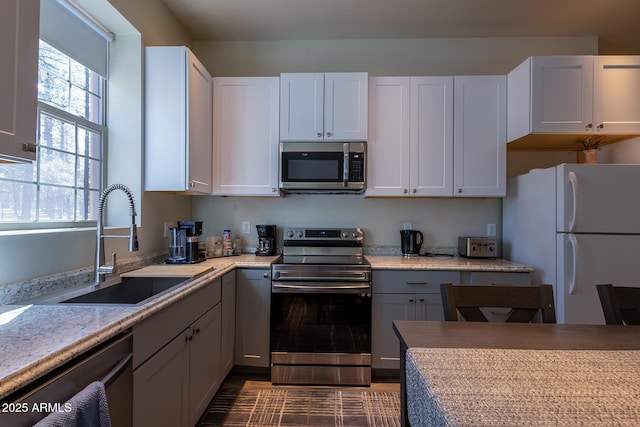 kitchen featuring light countertops, appliances with stainless steel finishes, a sink, and white cabinets