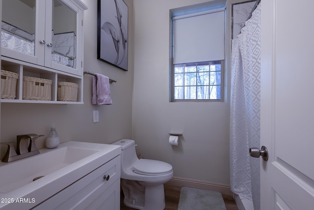 bathroom featuring toilet, vanity, and baseboards