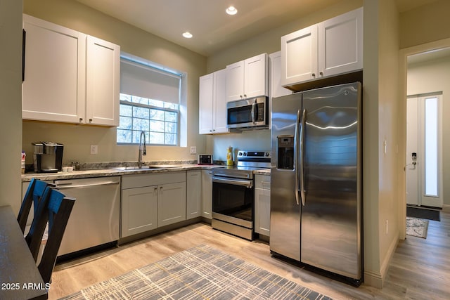 kitchen with recessed lighting, light wood-type flooring, a sink, and appliances with stainless steel finishes