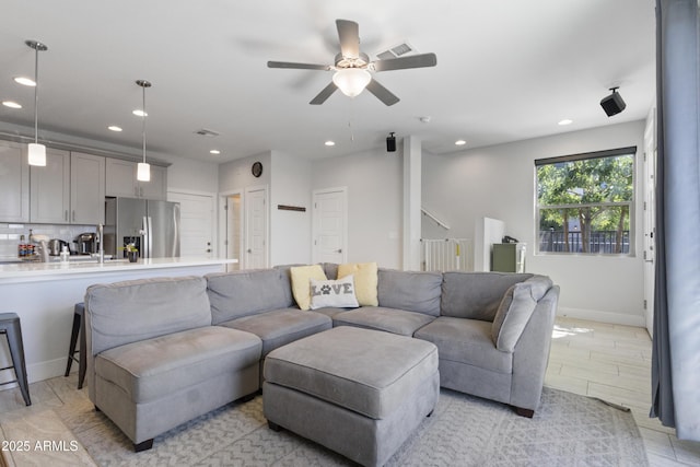 living room featuring baseboards, a ceiling fan, and recessed lighting