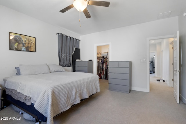 bedroom featuring a walk in closet, a ceiling fan, light colored carpet, baseboards, and a closet