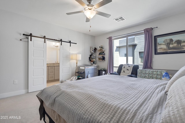 bedroom featuring visible vents, a barn door, baseboards, light carpet, and ensuite bath