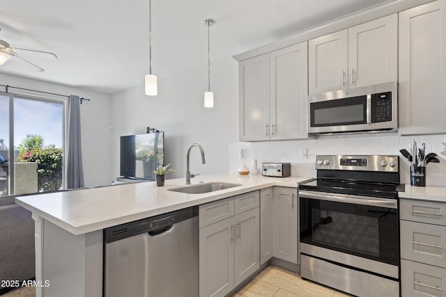 kitchen with tasteful backsplash, a sink, light countertops, a peninsula, and stainless steel appliances